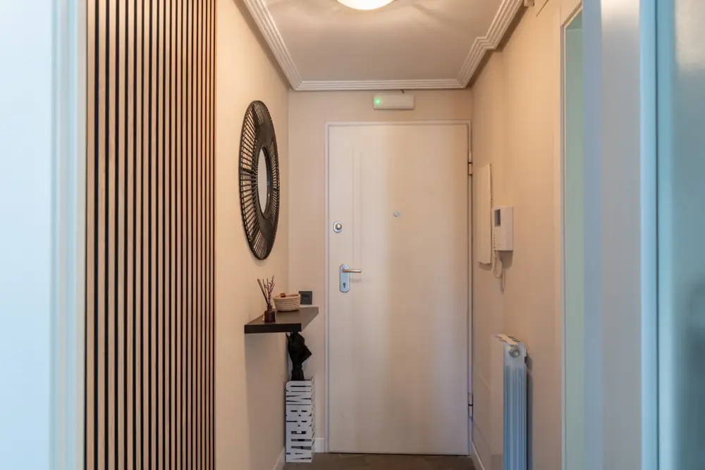 Ingresso dell’appartamento con listelli di legno e uno specchio rotondo